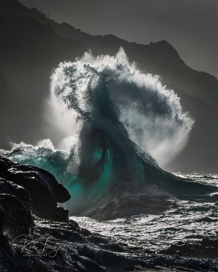 A large wave breaking against dark coastal cliffs